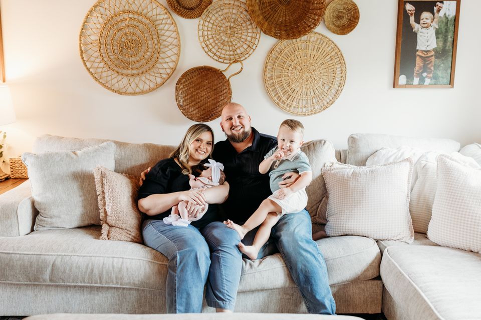 Logan and Brittany LeGrande on the couch at home with their two children.