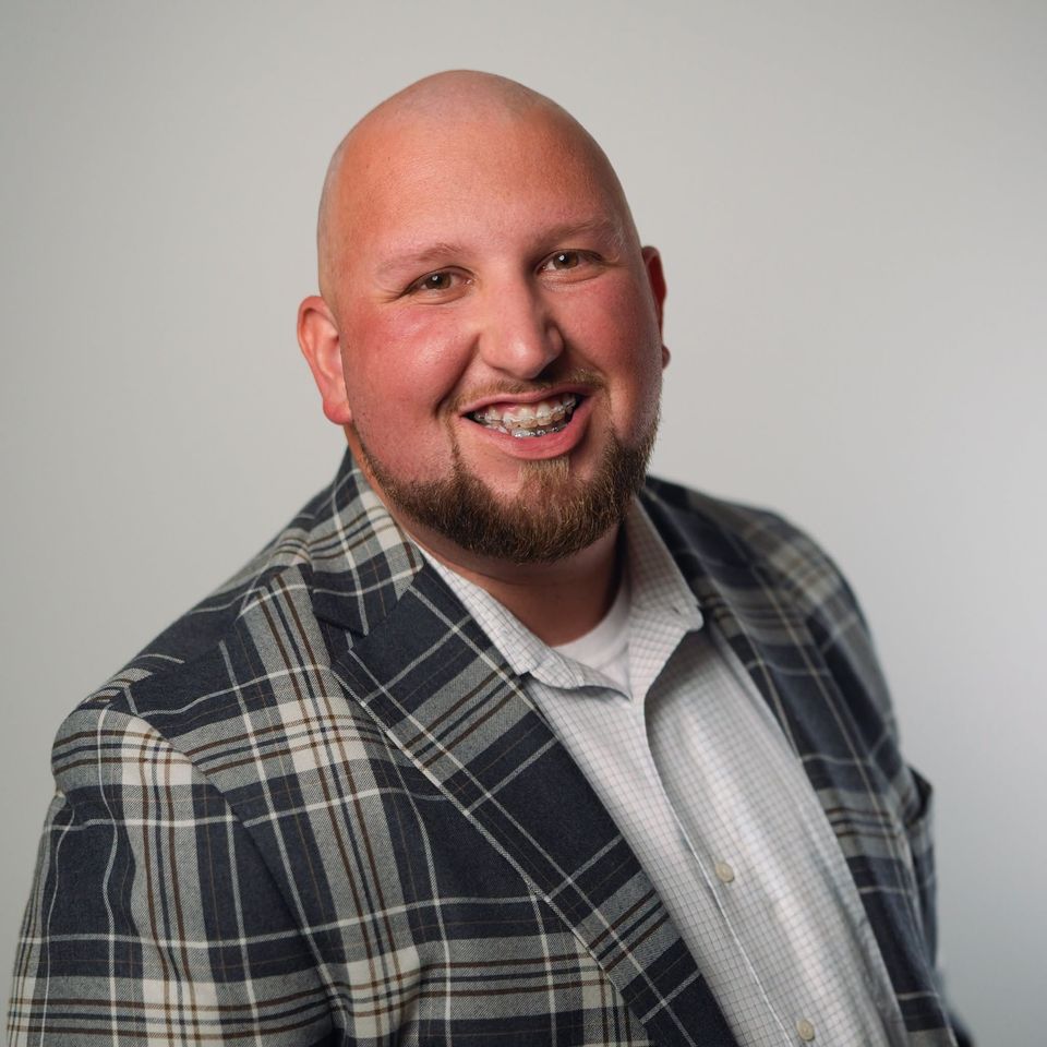 Logan LeGrande, smiling, in a plaid sport coat.